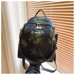 Detail of bamboo leaf print on black nylon backpack with elegant golden metal hardware