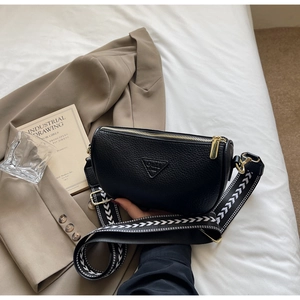 Macro shot of black lychee grain leather pillow bag with stylish wide geometric strap