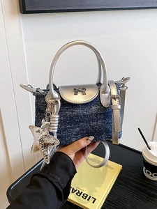 Polka dot denim handbag with silver metallic bow and star charm shown in hand