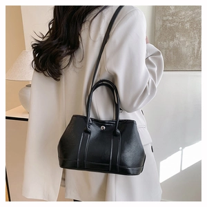 Détail d'un sac seau en cuir noir avec anneau en métal argenté et bandoulière longue