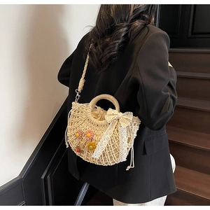 Lace straw basket bag with crochet flowers shown being worn over a dark blazer