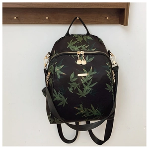 Detail of waterproof nylon backpack with green leaf print and golden metal zippers