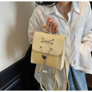 Détail du sac à dos en similicuir jaune avec fermoir papillon et breloques perles