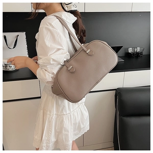 Detailed side view of taupe lychee-textured leather tote bag worn by a model