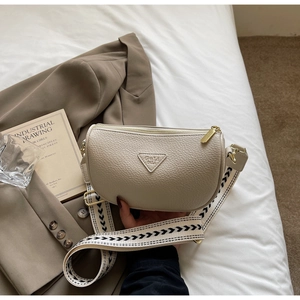 Detail of beige pillow bag with lychee texture and black and white wide shoulder strap