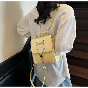 Détail d'un sac à dos en similicuir jaune avec pendentif papillon et perles