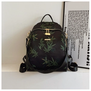 Detail of black backpack featuring green bamboo leaf prints and gold-tone zippers