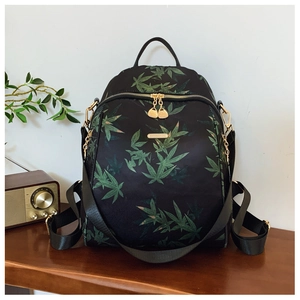 Detail of black backpack with green leaf pattern on a vintage wooden tabletop setting