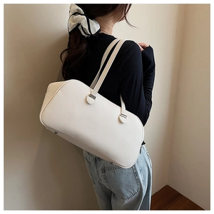 Detail of white lychee grain leather boston bag with silver hardware on model's shoulder