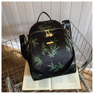 Detailed view of the green bamboo leaf print on a black nylon backpack in a casual setting