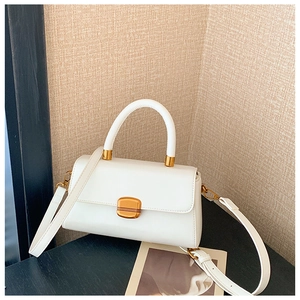 Detailansicht einer weißen Vintage-Handtasche mit goldener Metallschließe und schmalem Gurt