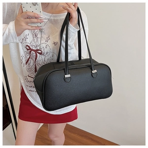 Close-up of black pebbled leather texture and silver hardware on minimalist handbag