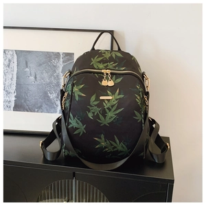 Detail of high-quality golden metal zippers and green leaf print on black backpack