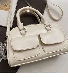 Close-up of beige faux leather Boston bag featuring front pockets and pearl lace charm
