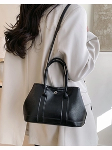 Sac seau minimaliste en cuir noir avec boucle argentée porté avec une tenue chic
