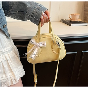 Detail of yellow lychee grain handbag with for you printed bow and curved handle