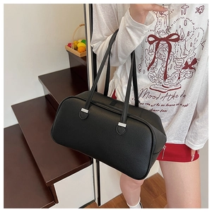Minimalist black pebbled leather boston bag with silver hardware on model shoulder