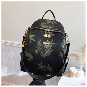 Detail of green bamboo leaf print on black nylon backpack with elegant gold hardware