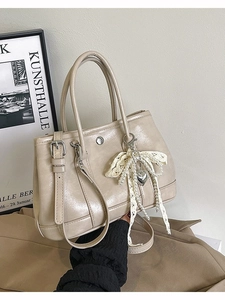 Sac seau beige élégant avec nœud en dentelle et perles sur fond de cadre vintage