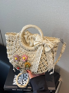 Lace straw bag with floral accents and red ladybug charm for summer beach vacation