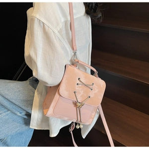 Détail du sac à dos en cuir verni rose avec œillets argentés et breloque papillon perlé