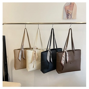 Detail of four litchi grain tote bags with decorative scarves on a metal rack