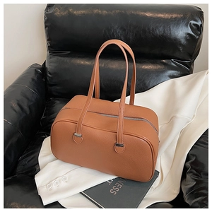 Close-up of caramel brown lychee leather handbag on magazine showing premium texture