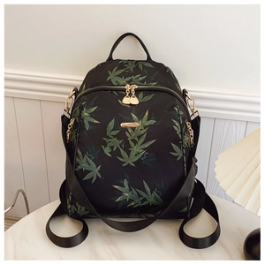 Detail of bamboo leaf print on black backpack with elegant gold brand metal plate
