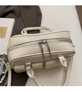 Detail of silver smooth two-way metal zippers on a beige vintage crossbody bag