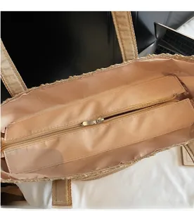 Dettaglio della chiusura lampo in metallo e della fodera interna di una borsa in paglia