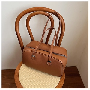 Detail of caramel lychee leather texture and silver hardware on a Boston handbag