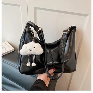 Detail view of glossy black PU leather tote bag featuring a cute white cloud plush pendant