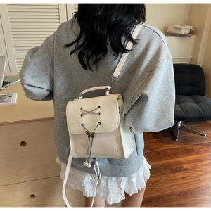 Lifestyle shot of cream PU backpack with ribbon lacing, butterfly clasp and pearl tassel