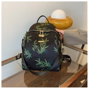 Detail view of black waterproof backpack with green leaf pattern and gold metal zippers