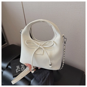 Détail du sac beige en cuir PU avec nœud décoratif et bandoulière en chaîne argentée