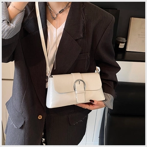 Detailed view of white minimalist leather underarm bag with silver round metal buckle
