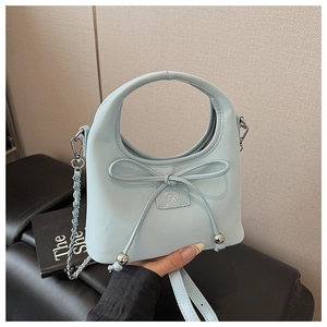 Détail d'un sac à main bleu clair avec décoration de nœud et chaîne en métal argenté