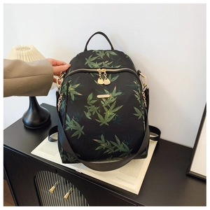 Detail of high-density nylon backpack featuring green leaf pattern and gold hardware