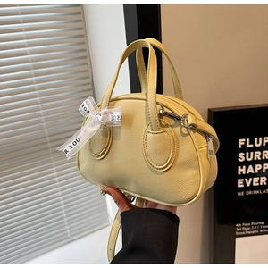 Detailed macro view of yellow lychee grain leather handbag with decorative bow accessory