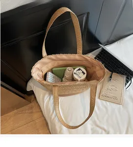 Dettaglio della grande borsa tote in paglia con interno spazioso, tasca con zip e oggetti