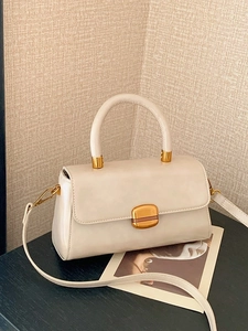 Elegante cremeweiße Lederhandtasche mit goldener Schnalle in stilvollem Ambiente