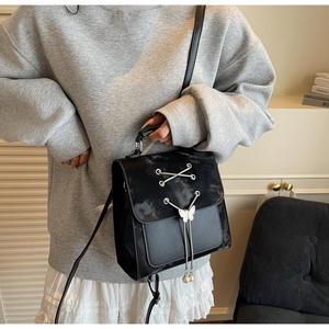 Détail d'un sac à dos rétro noir avec breloque papillon argentée et gland de perles