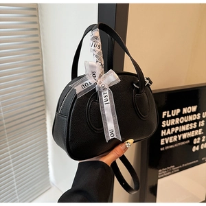 Detail of black lychee grain leather bowling bag with silk ribbon decoration and silver zippers