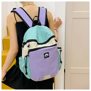 Detailed back view of a woman wearing the tricolor pastel nylon backpack in mint and white