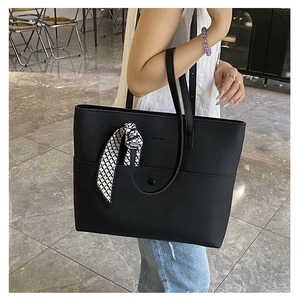 Detail of black pebbled leather tote with CHCH & BAGS logo and decorative silk scarf