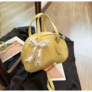 Detail of a yellow semi-circular handbag with a lychee texture and ribbon bow