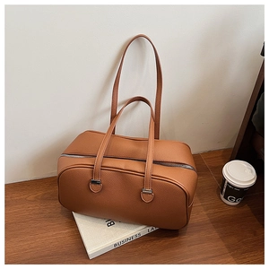 Close-up of brown litchi pattern leather handbag with dual handles on a wooden table