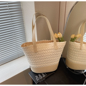 Dettaglio della borsa tote in paglia intrecciata con inserti in pizzo color crema