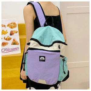 Close-up of tricolor patchwork backpack featuring side drawstring pockets and logo detail