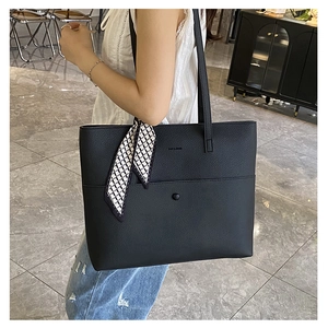 Close-up of black litchi grain leather tote bag with stylish geometric pattern scarf detail